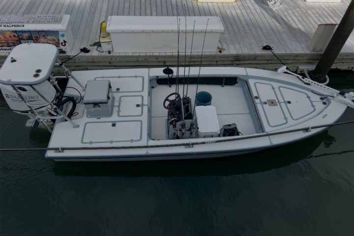 Top view of a small fishing boat docked, with fishing rods and equipment visible.