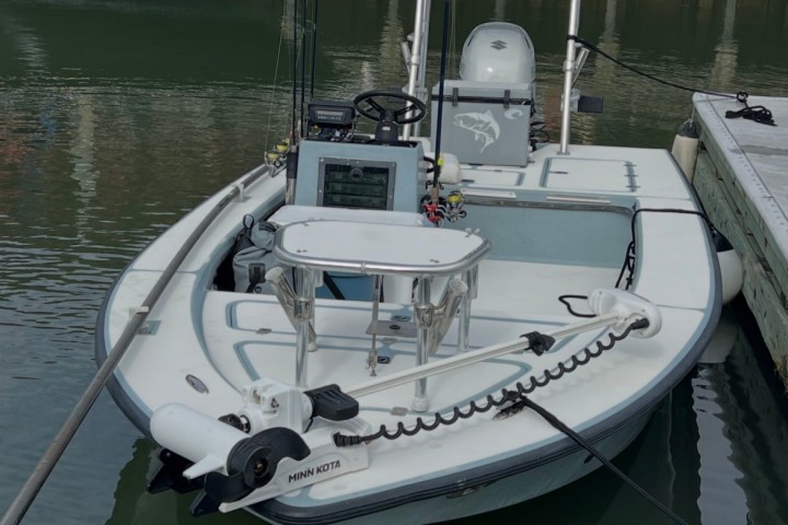 Small fishing boat docked, equipped with Minn Kota motor and fishing rods.