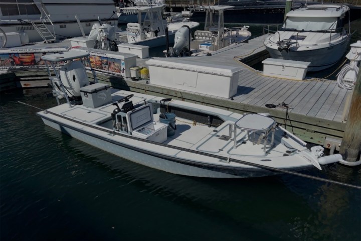 A small fishing boat docked at a marina beside larger boats.