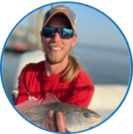 Person wearing sunglasses holding a fish on a boat.